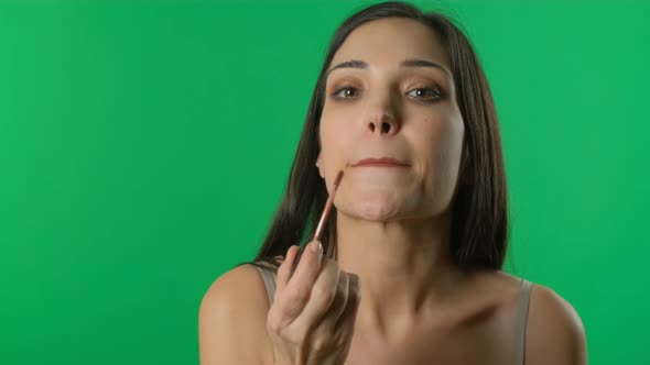 Woman Applying Lipstick Looking at Mirror. Lips Makeup Close Up. Girl Does a Make-up in Green Screen alt