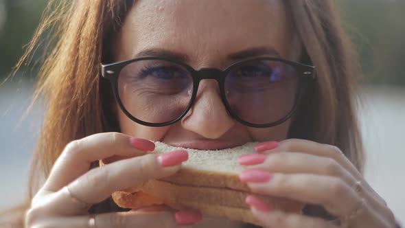 Closeup of Girl with Glasses Eats Sandwich