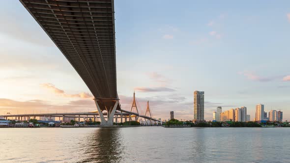 Large suspension bridge over Chao Phraya river at twilight, day to night - time lapse