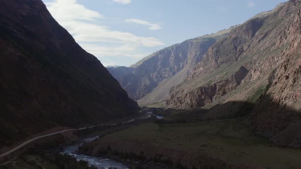 River Chulyshman between green field and mountains with blue clear sky in Altai