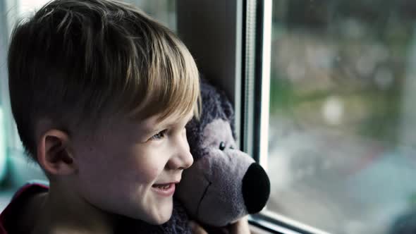 Little Boy Smiling Looking Out the Window Child Looks Out the Window on a Rainy Day