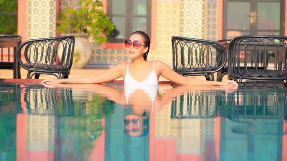 Young asian woman enjoy around outdoor swimming pool for leisure alt