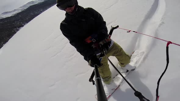 A young man snow kiting on a snowboard. alt