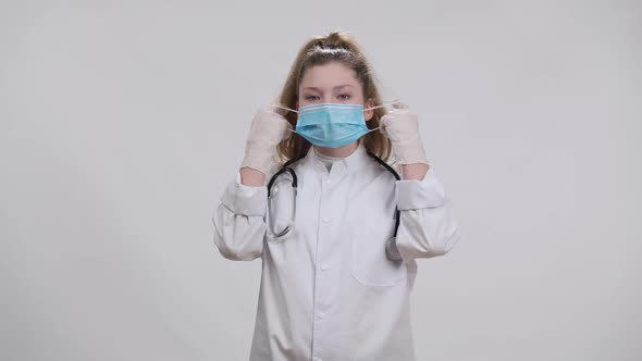 Overworked Exhausted Little Doctor Taking Off Covid19 Face Mask Sighing Looking at Camera alt