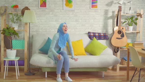 Pretty Muslim Woman in a Hijab Learns About Winning Using a Smartphone and Dances alt