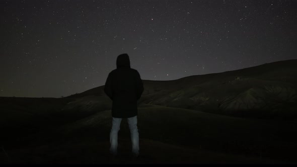A Man Stands Against the Background of the Night Sky with Stars alt