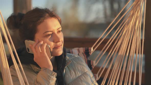 A Young Woman with Dark Hair is Talking on the Phone Enjoying a Spring Sunset