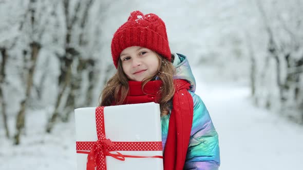Adorable Little Girl With Christmas Box Gift in Winter Outdoors