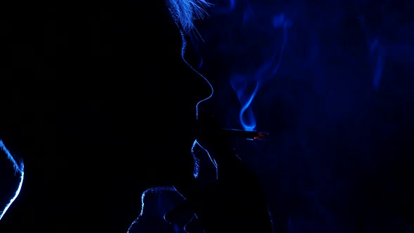 Portrait of a Bearded Man with a Cigarette. Back Light. Silhouette alt