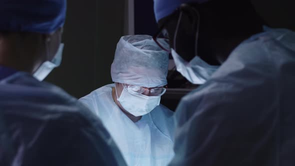 Surgeon and interns standing around operating table