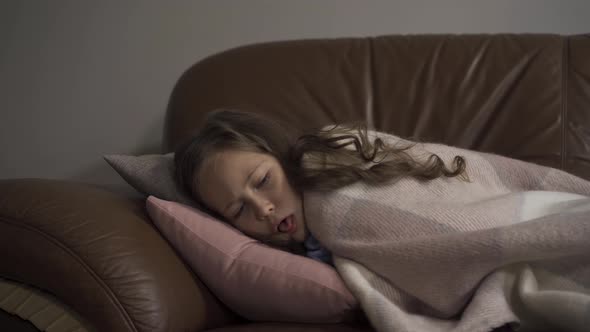 Sick Young Caucasian Girl Coughing While Lying Under Blanket at Home. The Child Has Fever. Concept alt