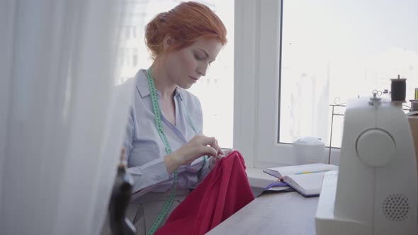 Successful Woman Sews at the Table in Workshop alt