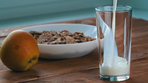 Pouring Milk Into a Glass for Breakfast with Oatmeal in Slow Mo alt