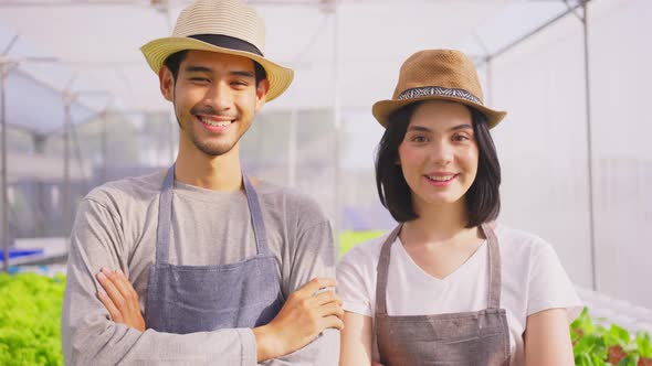 Asian couple farmers owner working in hydroponic green house farm with happiness and look at camera. alt