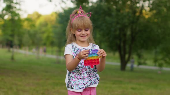 Child Girl Kid Loses on Mobile Phone Game Use Squishy Silicone Antistress Pop It Toy to Calm Down alt
