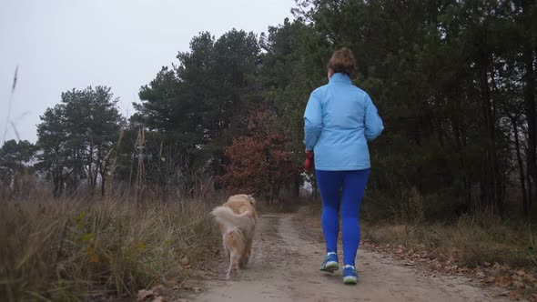 Female Trail Runner with Pet Jogging in the Wood alt