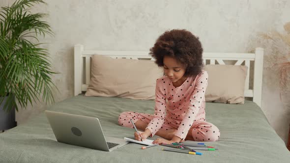 Cute Little African American Girl Busy in Writing or Learning to Draw with Felt Tip Pens By Looking alt