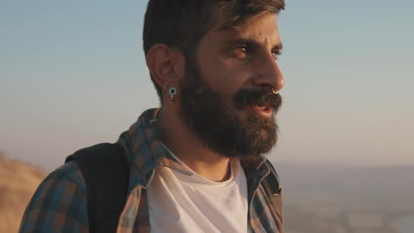 Man walking with a backpack at sunset alt