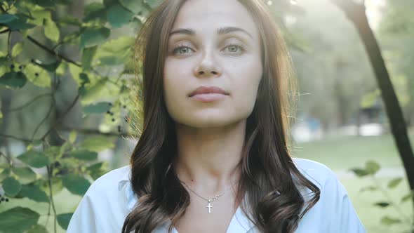 Front Shot Near a Pretty Girl with Long Beautiful Hair Standing in a Park Among Trees in Sunny alt