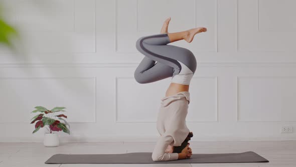 Side view of Asian woman doing Yoga exercise in front of windows alt