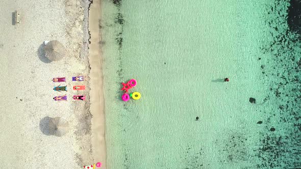 Aerial view of people lying in yoga pose on on the with inflatables on beach. alt