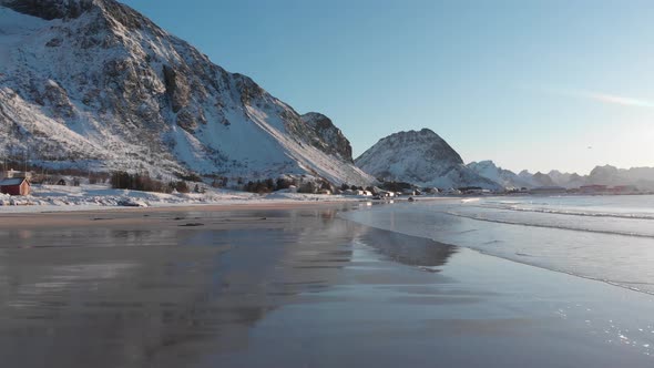 Ramberg beach during winter covered by snow in the Lofoten. Mountains reflection in the water.