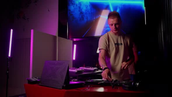 Young adult male person jockey mixing music on controller console. DJ work in club indoor alt