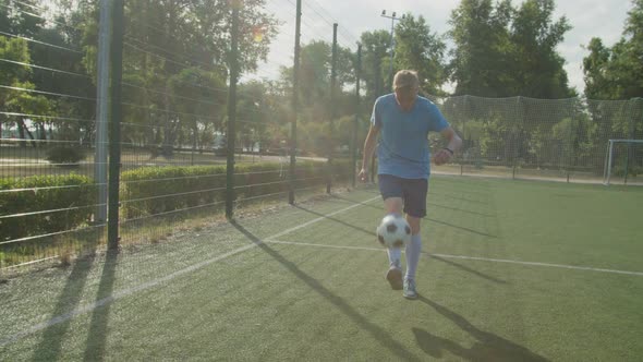 Footballer Practicing Ball Control and Coordination on Sports Field alt