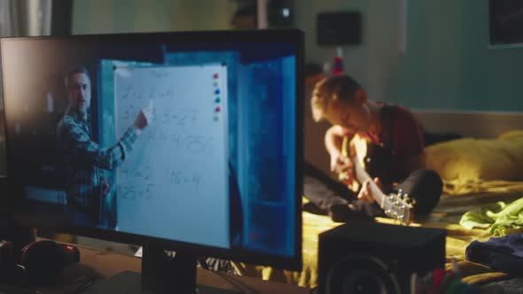 Teen Guitarist Rehearsing During Online Lesson alt