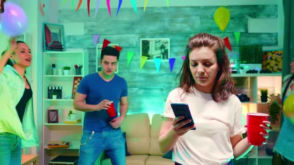 Bored Girl Texting on Her Smartphone at His Friends Party alt