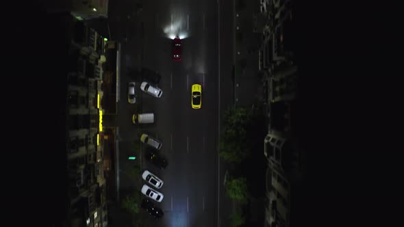 A beautiful sports car drives at night along modern city streets among skyscrapers and houses.  alt