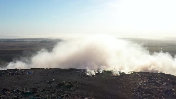 Aerial view of smoke from burning garbage pile in landfill, Earth pollution concept alt