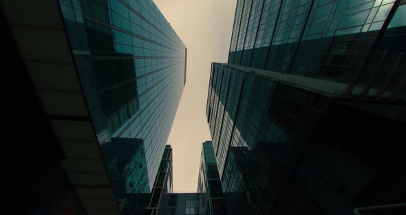 Low Angle of the Facades of Skyscrapers with Clouds and Blue Sky in Reflection alt