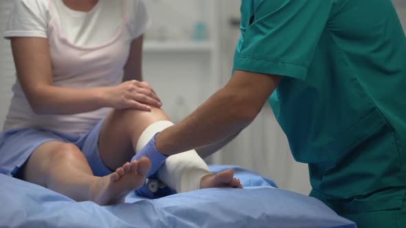 Male Surgeon Applying Elastic Wrap on Female Patients Leg, Rehabilitation Period