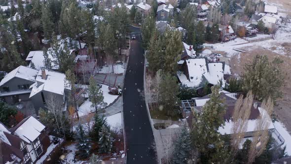 Car Driving Through Small Picturesque Snowy Neighborhood at Winter Time, Aerial Shot alt