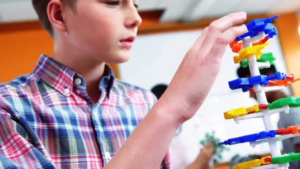 Schoolboy experimenting molecule model in laboratory at school alt