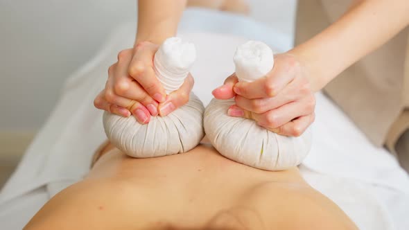 Asian beautiful woman enjoy thai hot compress massage with herbal bags. alt