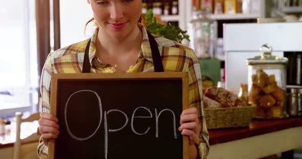 Portrait of waitress showing chalkboard with open sign alt