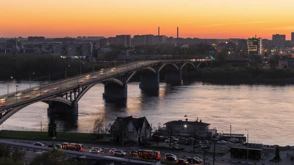 Time lapse view on bridge over the river with moving cars at sunset