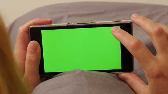 Woman with finger changing pages on green screen smart phone  4K 3840X2160 UltraHD footage - Female  alt