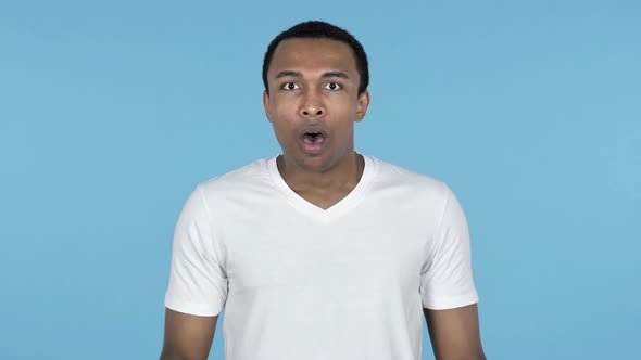 Shocked Surprised Young African Man Standing Blue Background in Wonder alt