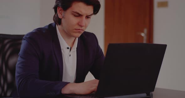 Tensed Young Businessman Using Laptop in Office alt