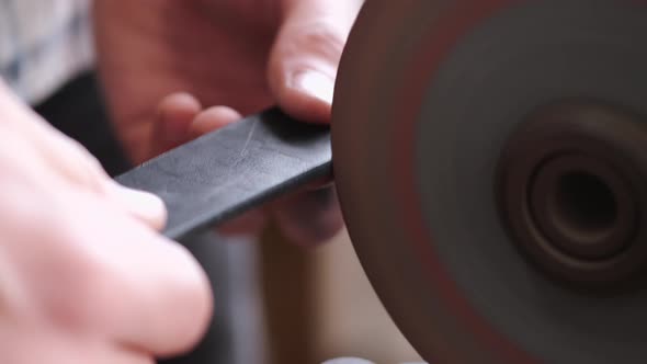 The Craftsman Is Sharpening the Edges of a Belt on a Special Machine alt