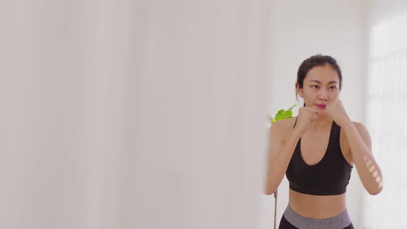 Athletic Healthy Asian young woman in sportswear workout boxing excercise training at home alt