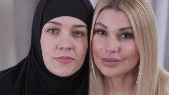 Close-up Faces of Muslim Woman in Hijab and Caucasian Blond Lady. Two Different Women From Different alt