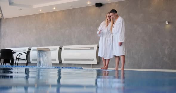 Romantic Couple in White Robes Hugs Standing on Pool Edge