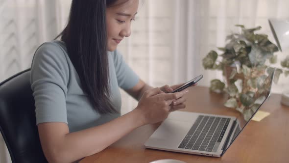 Asian woman smiling hands typing mobile phone and scrolls through social media feeds in a smartphone