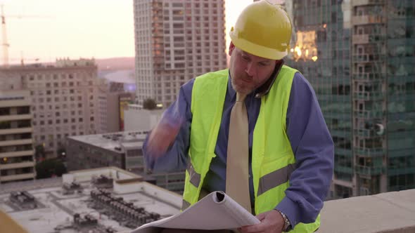Construction manager on rooftop using looking at plans