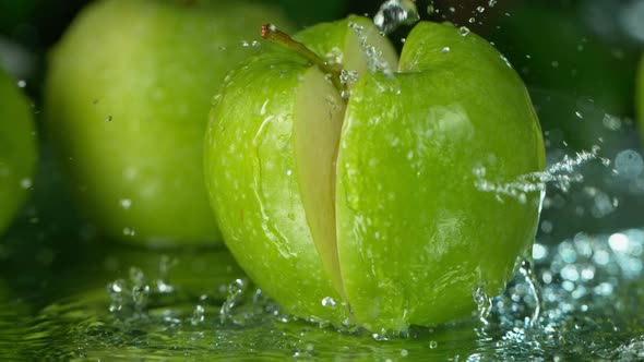 Super Slow Motion Shot of Falling Fresh Cutted Apple with Water Splashing at 1000Fps alt