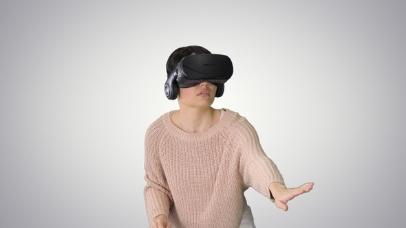 Cute young woman walking and using interactive VR headset alt
